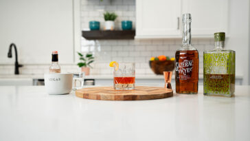 a glass of Sazerac cocktail with ingredients as background