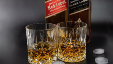 Two glasses of whiskey on the background of a bottle of wiskey Johnnie Walker, Red Label and Black Label.